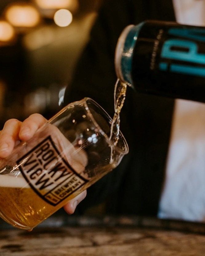 A server pouring an IPA into a glass.