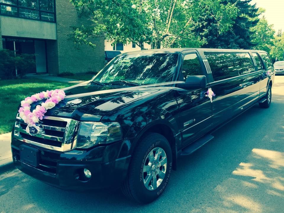 Black stretch limo with purple and white flowers on street, part of Signature Limos fleet.