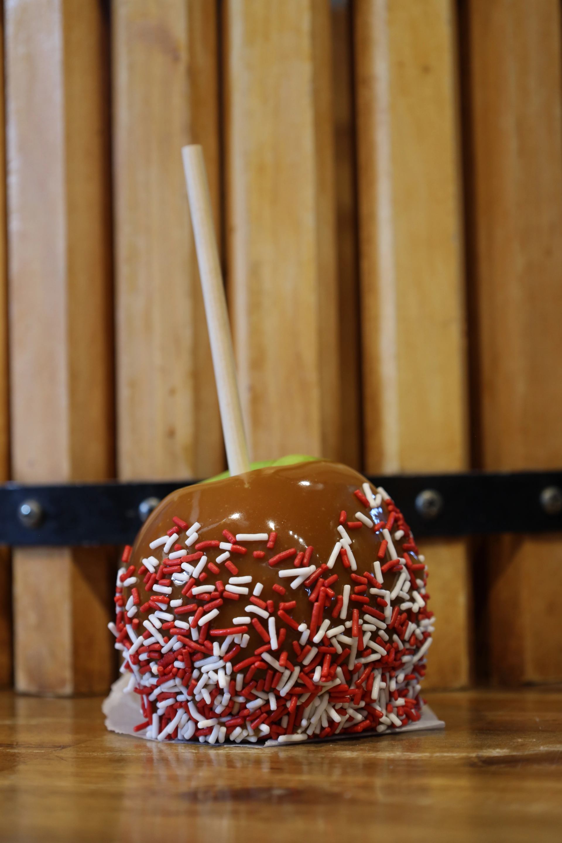 Caramel apple with sprinkles on wooden surface at Granary Road.