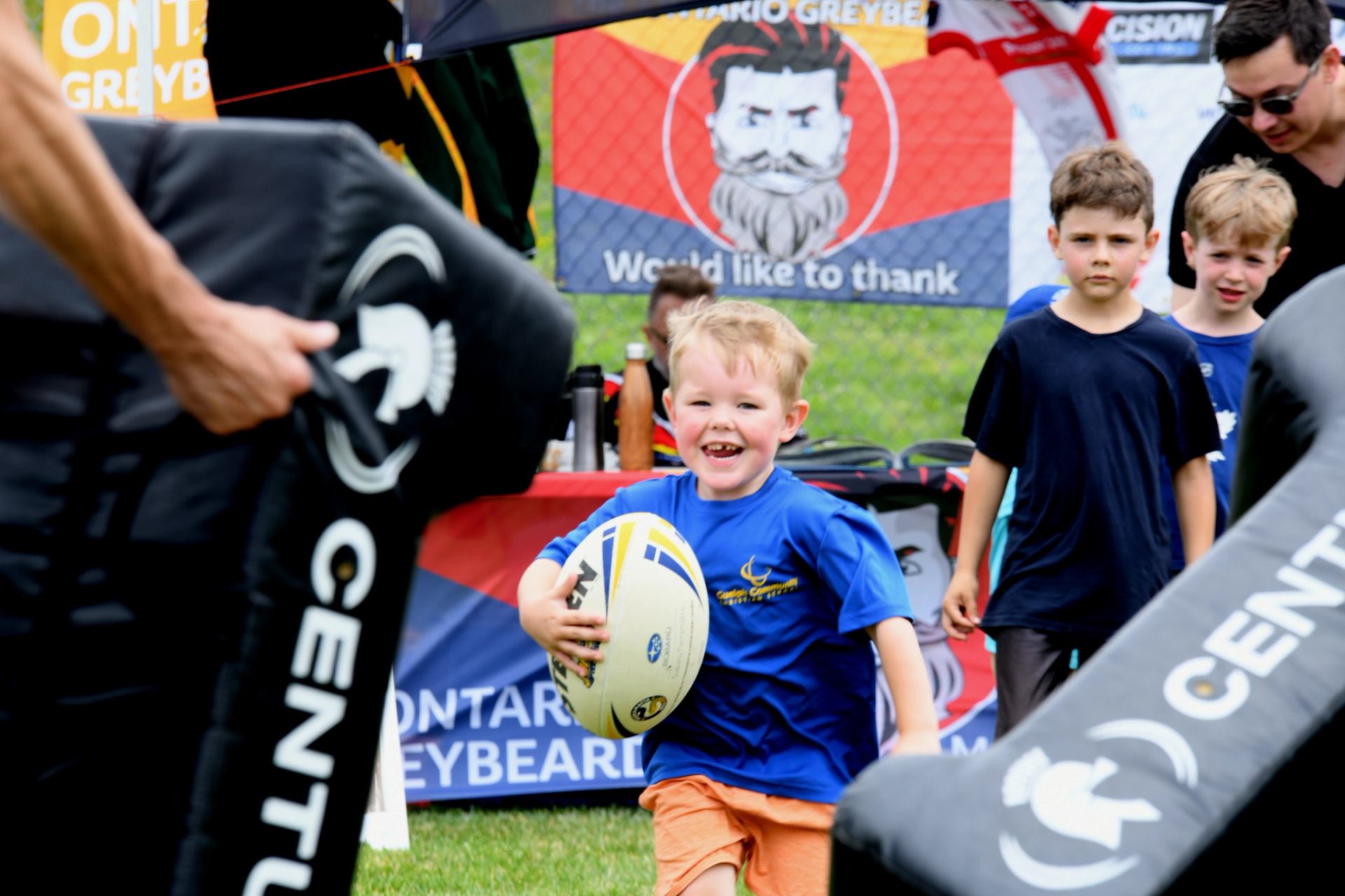 Child runs with rugby ball through obstacle course at The Good Games.