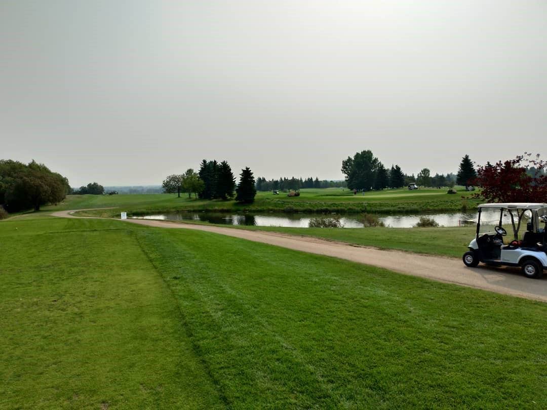 Golf cart parked near water on a sunny day at Raven Crest.