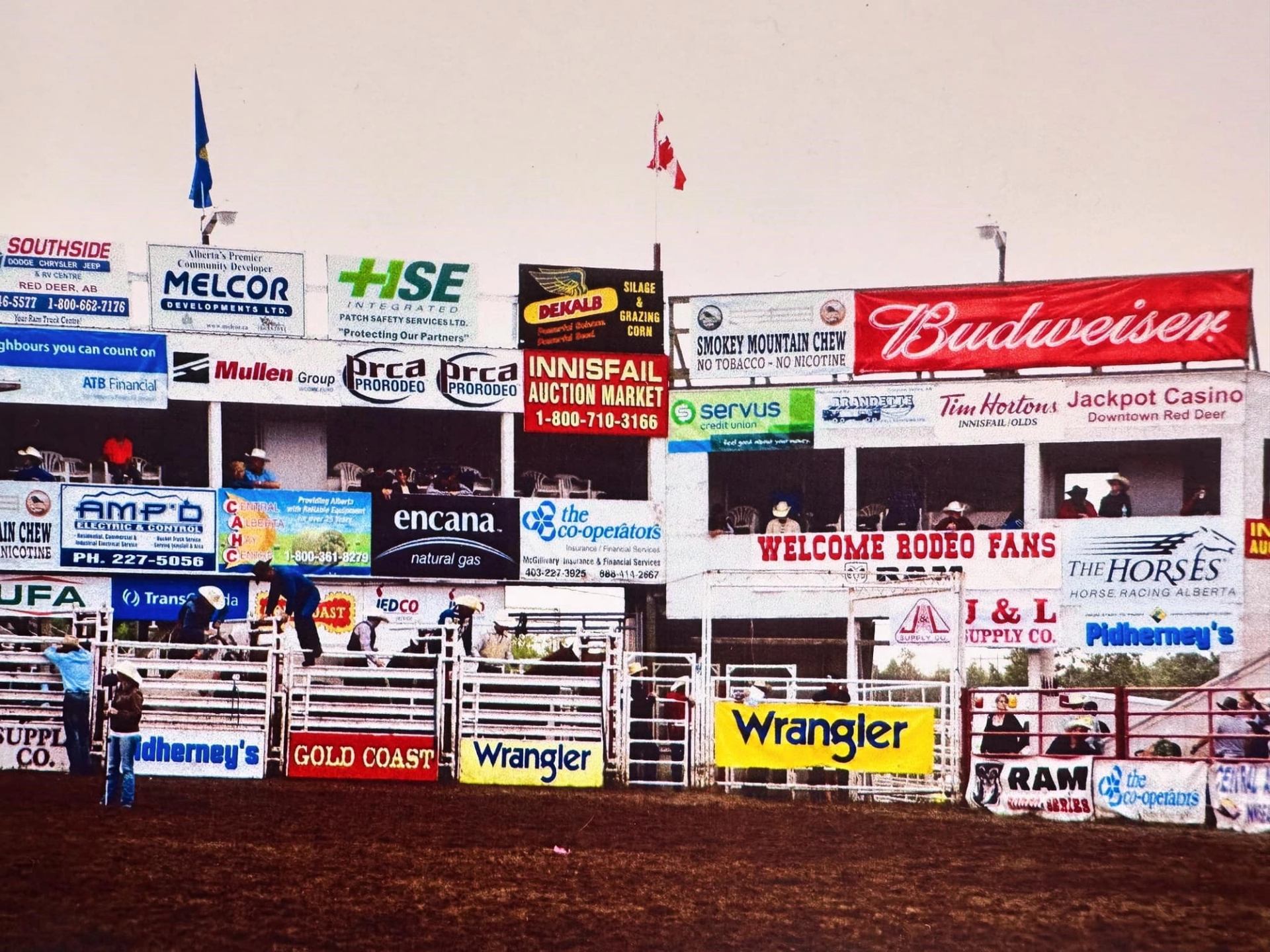 Rodeo arena fencing and gates lined with sponsor signage and a welcome message at the Daines Ranch Pro Rodeo.