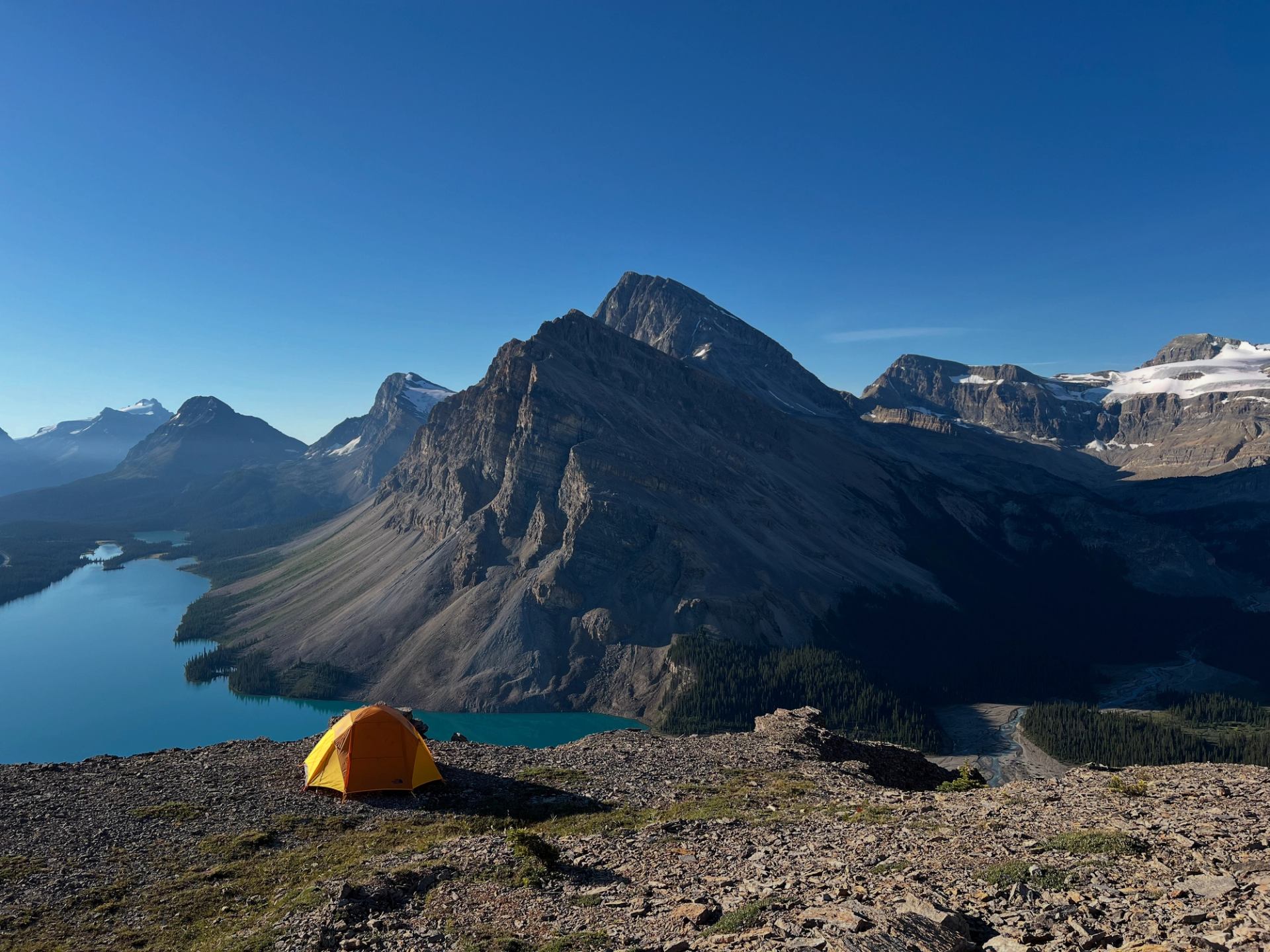 Tent on high ridge overlooking deep blue lakes and towering peaks
