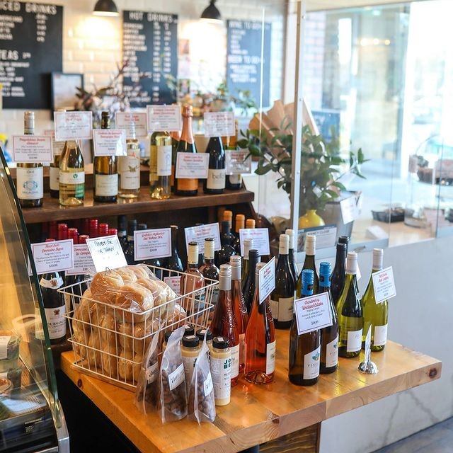 Wine bottles with price tags and packaged bread on a wooden table.