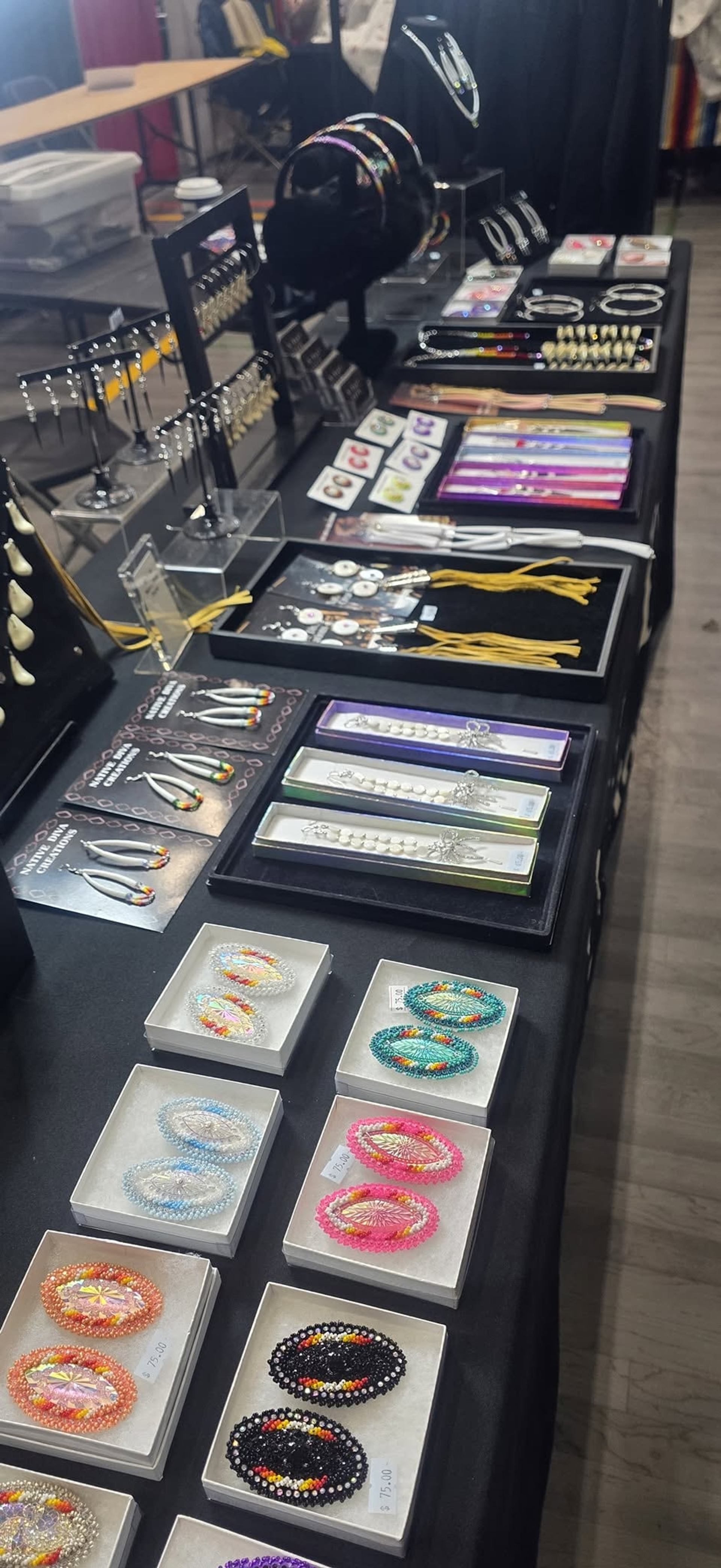 Display table with beaded earrings, bracelets and jewellery laid out in organized rows.
