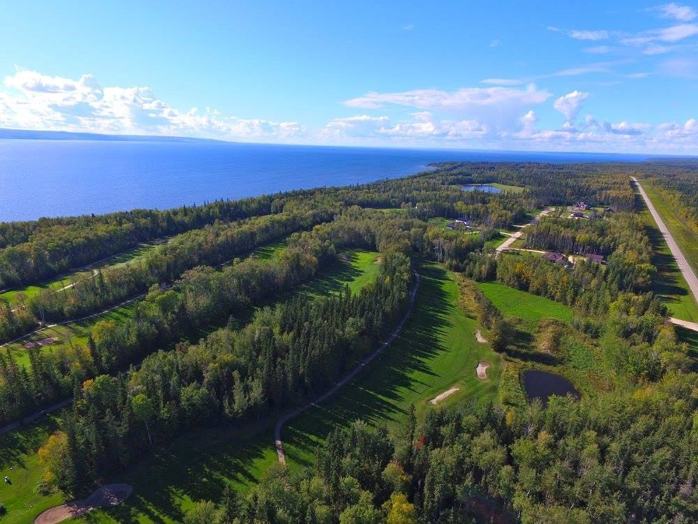 Aerial view of Gilwood Golf and Country Club course overlooking forest and lake.