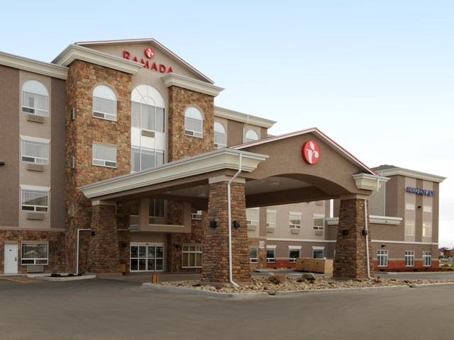 Exterior of Ramada Inn Olds with covered entrance and visible signage.
