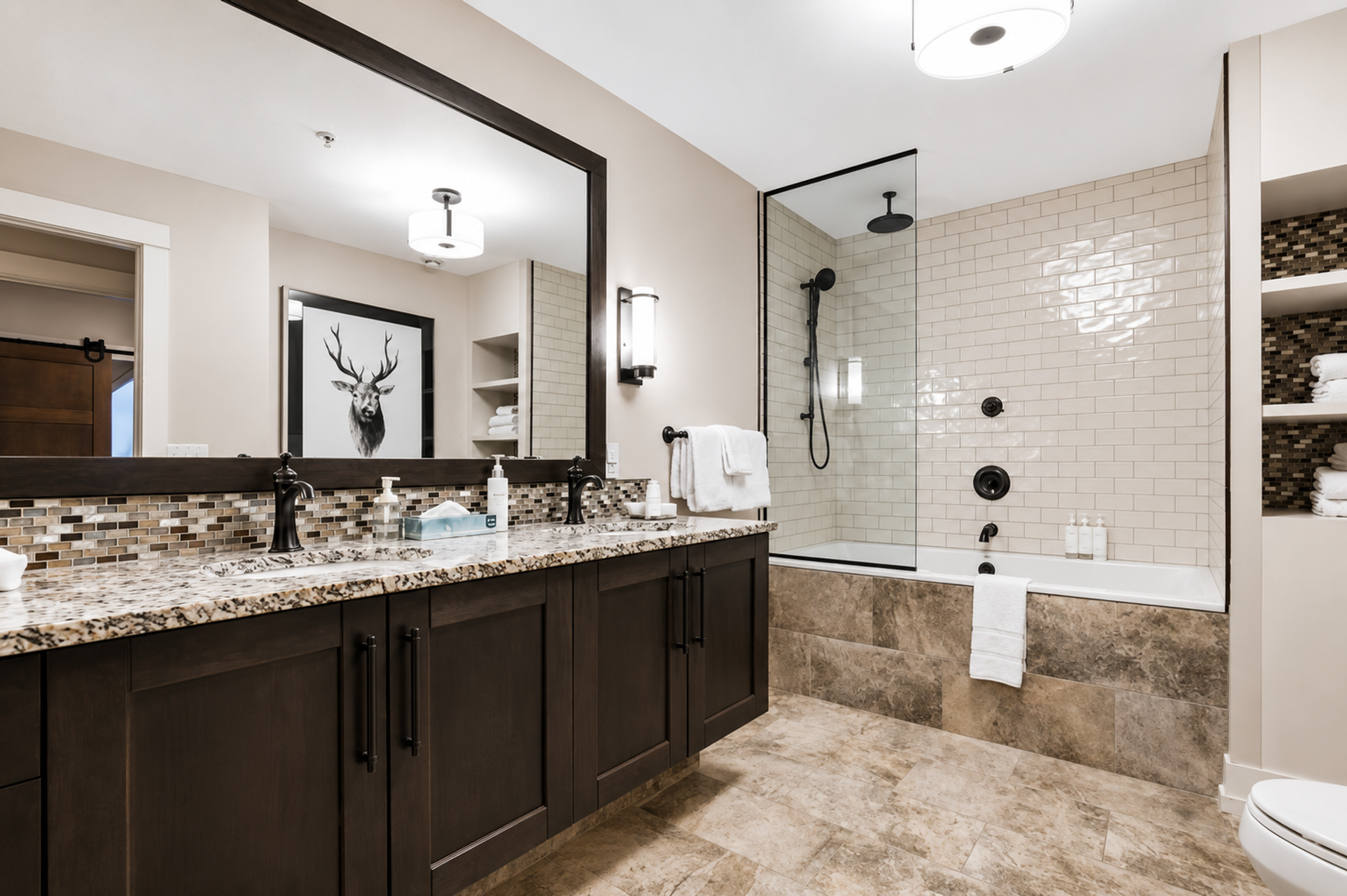 Bathroom with double vanity, large mirror and tiled tub-shower enclosure.