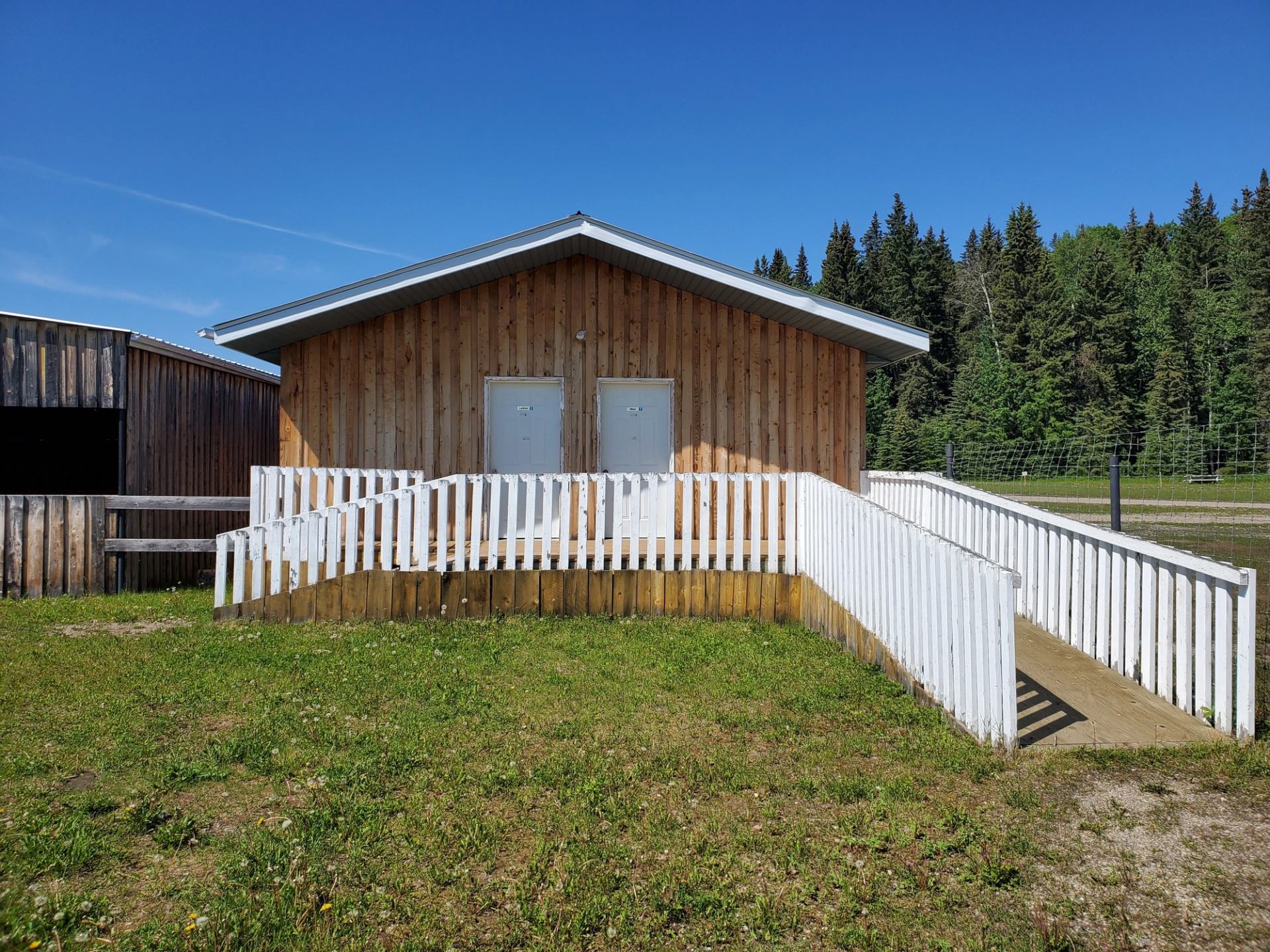 Wooden cabin with white ramp at Medicine Lodge Campground, surrounded by trees.