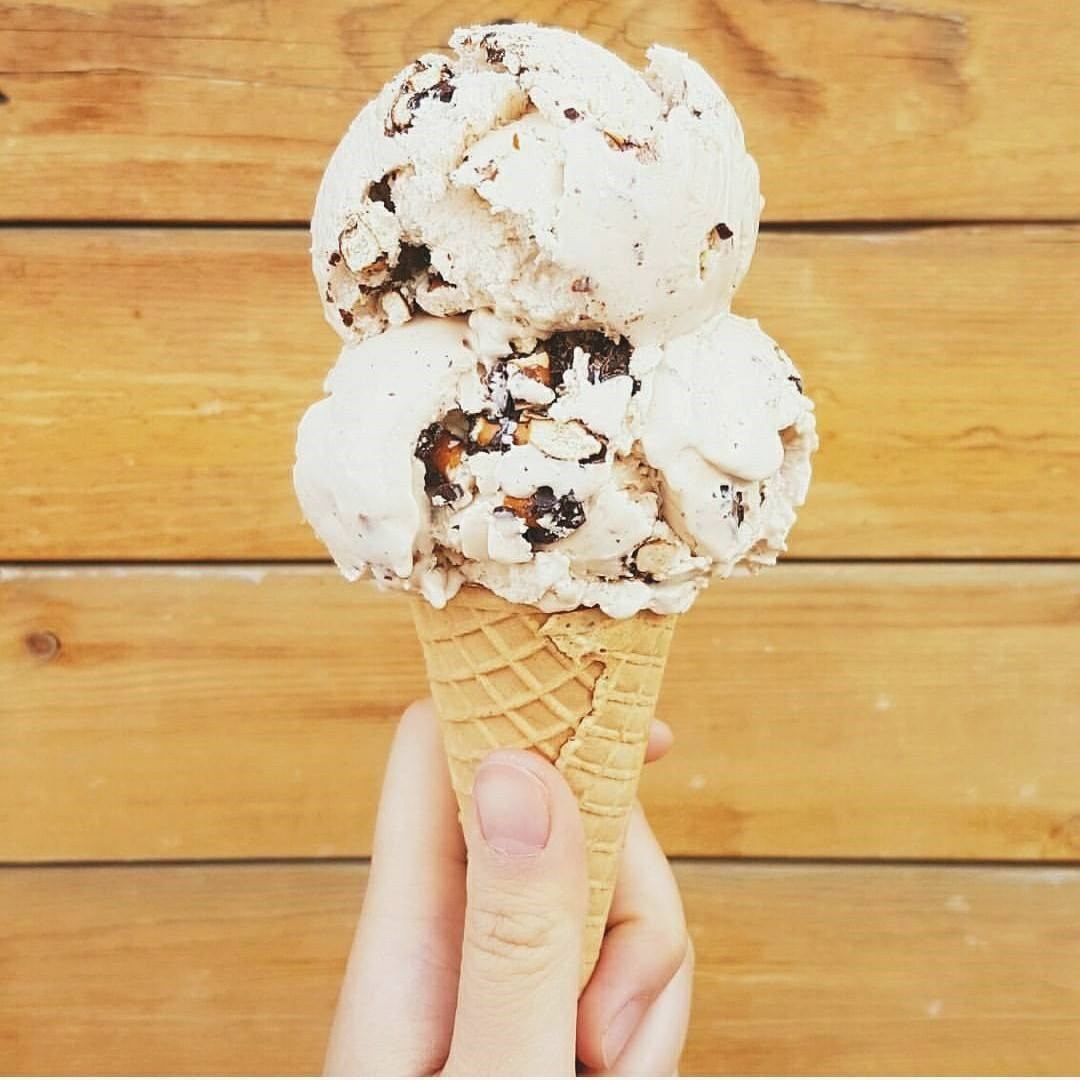 Cone holding two scoops of chocolate chip ice cream against wooden background.