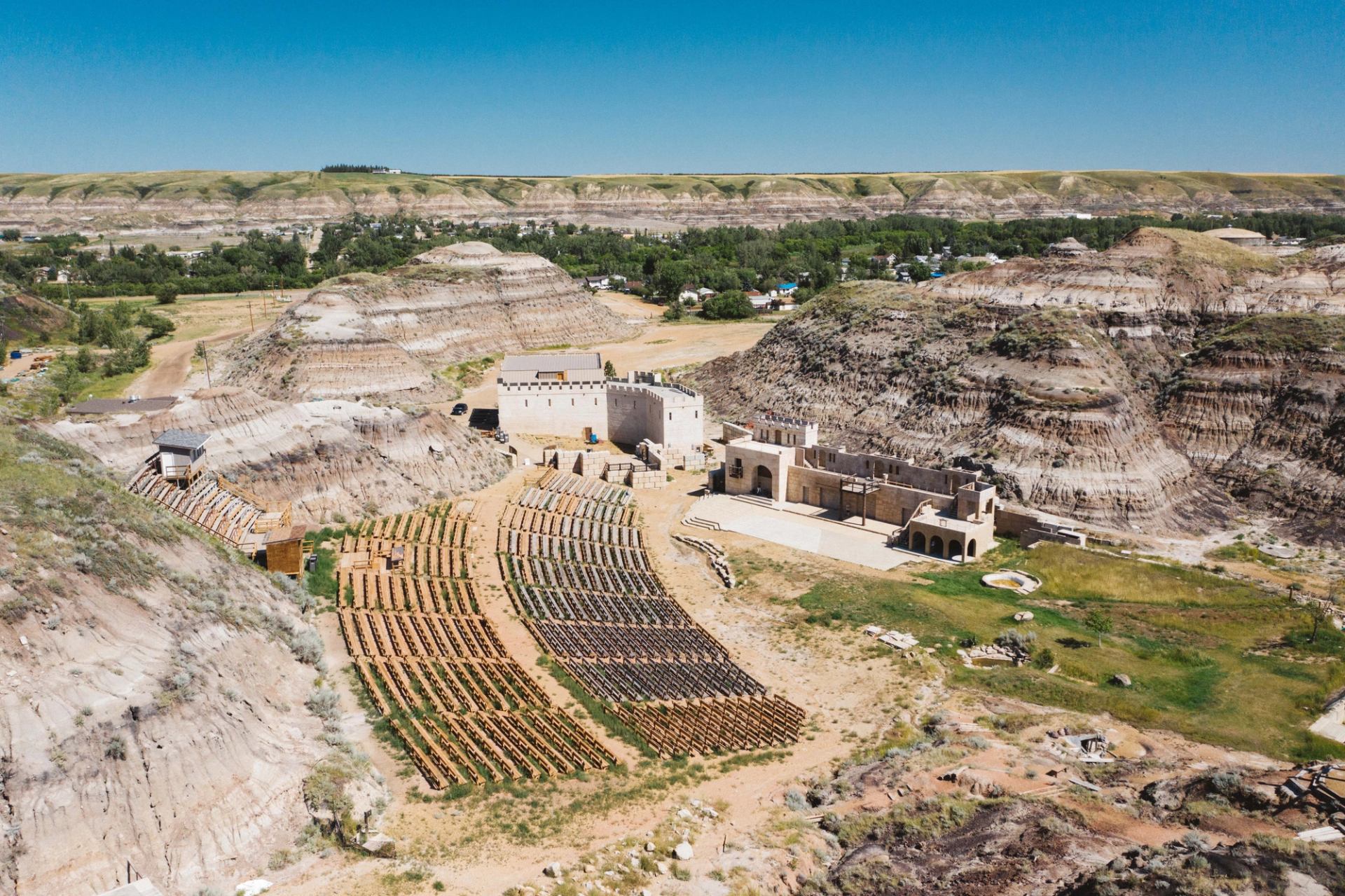 Aerial view of an outdoor amphitheater and stage built into a dry, layered rock canyon.