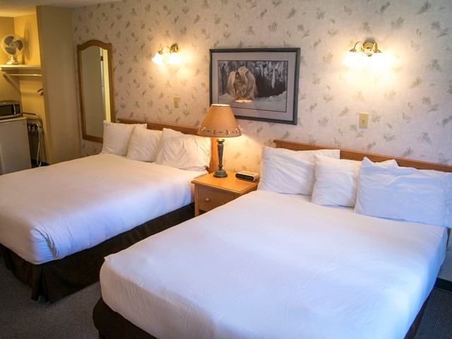 Hotel room with two double beds, warm lighting, and classic decor.