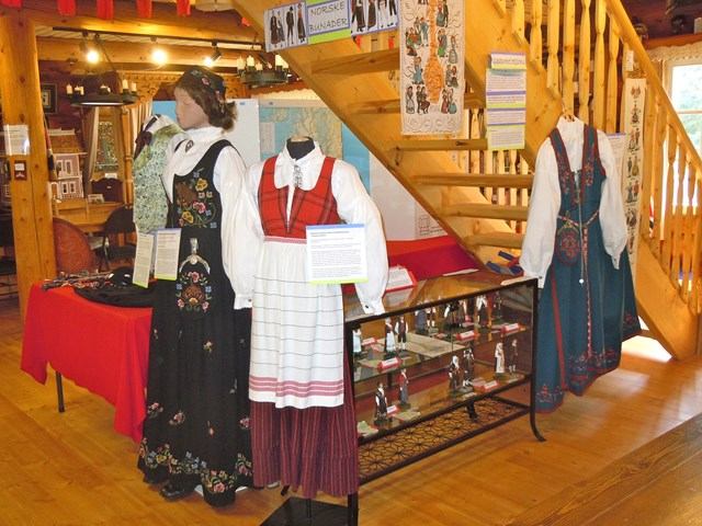 Mannequins in embroidered traditional attire at Norwegian Laft Hus cultural exhibit.