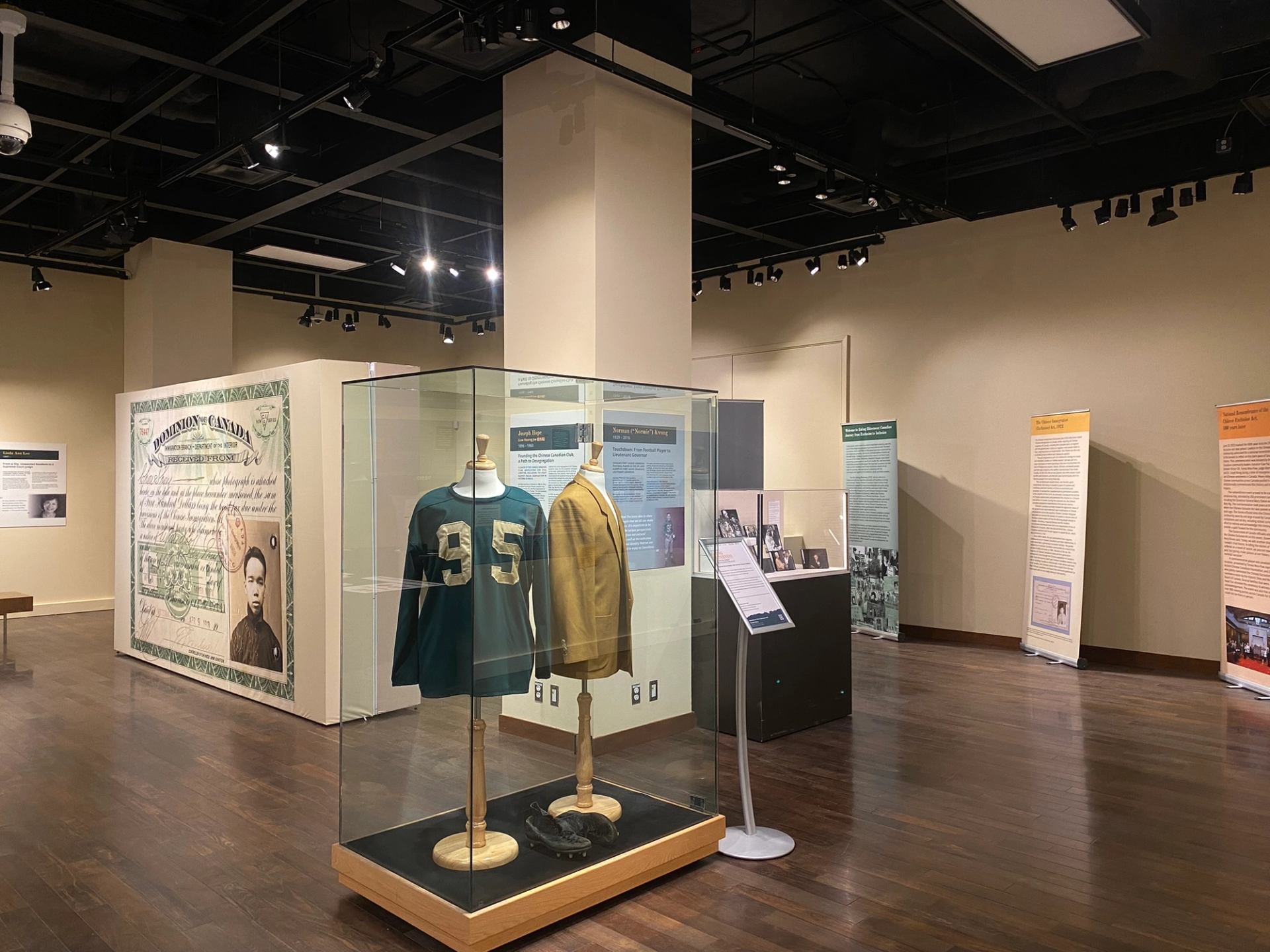 Museum exhibit with vintage sports jerseys in glass case and historical information panels.