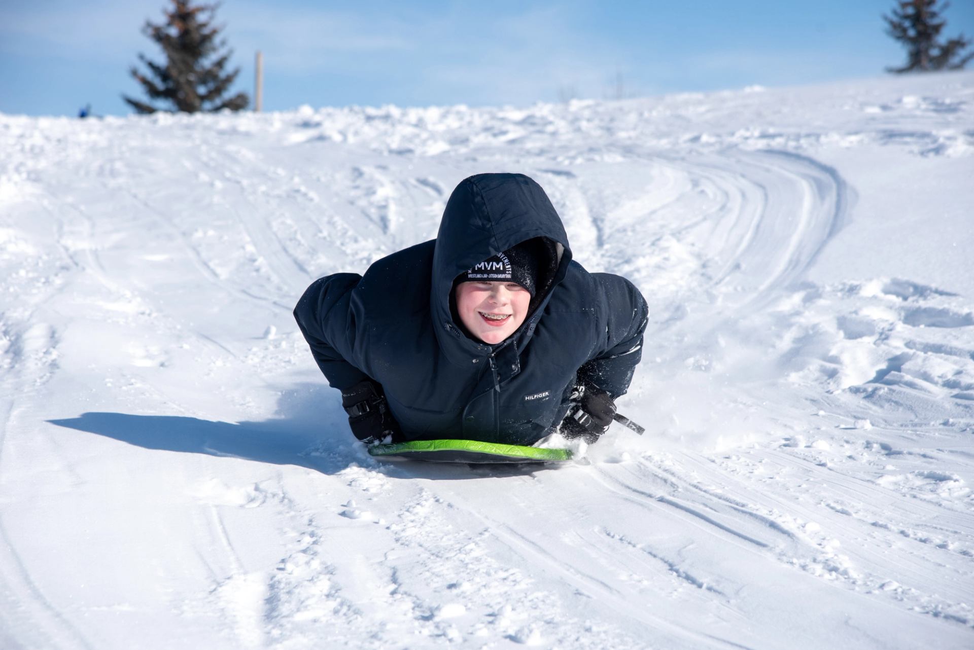 A young boy enjoys sliding down a smooth sledding hill in Camrose.