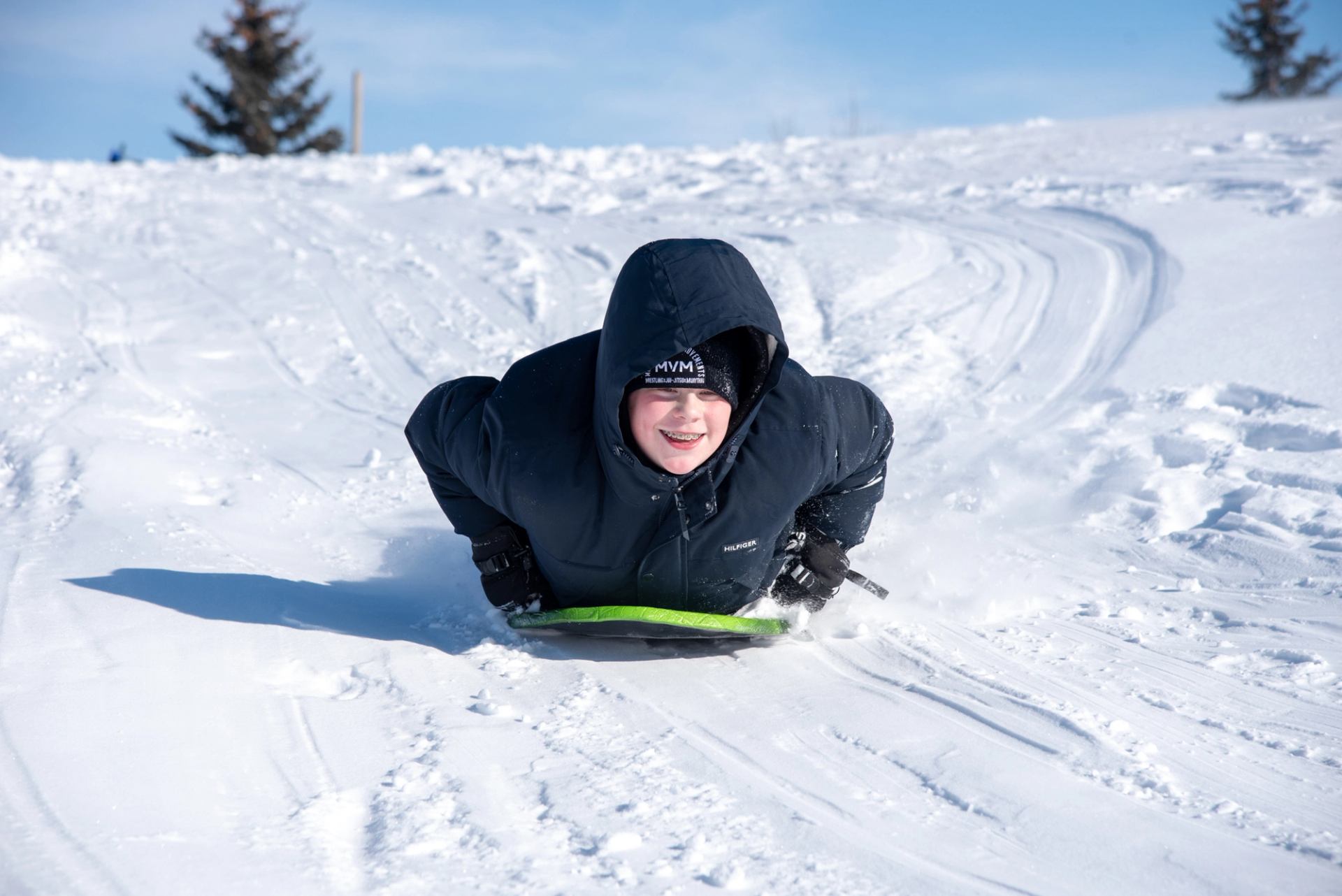 A young boy enjoys sliding down a smooth sledding hill in Camrose.