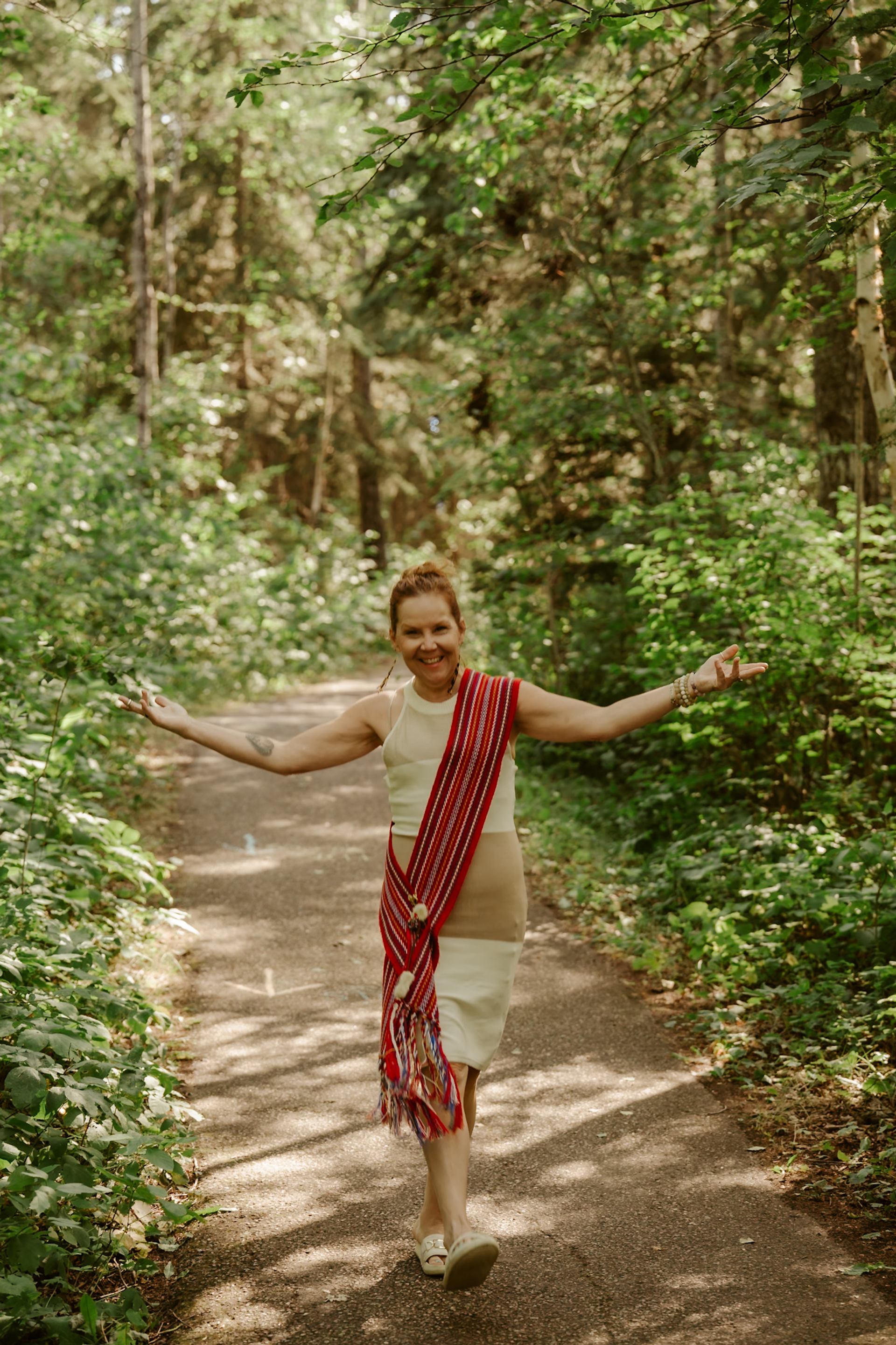 Individual wearing traditional fabric walking along a forest trail.