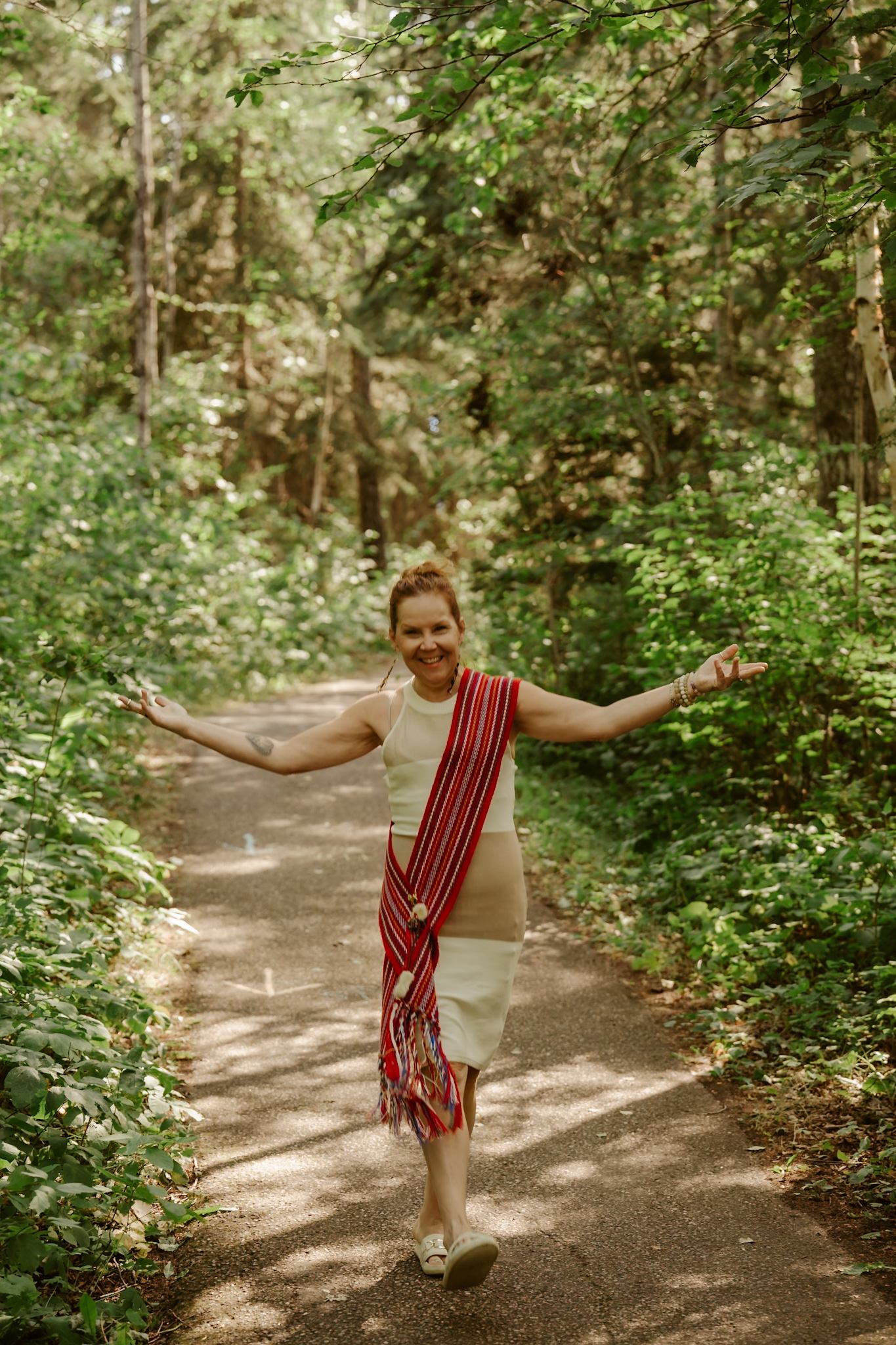 Individual wearing traditional fabric walking along a forest trail.