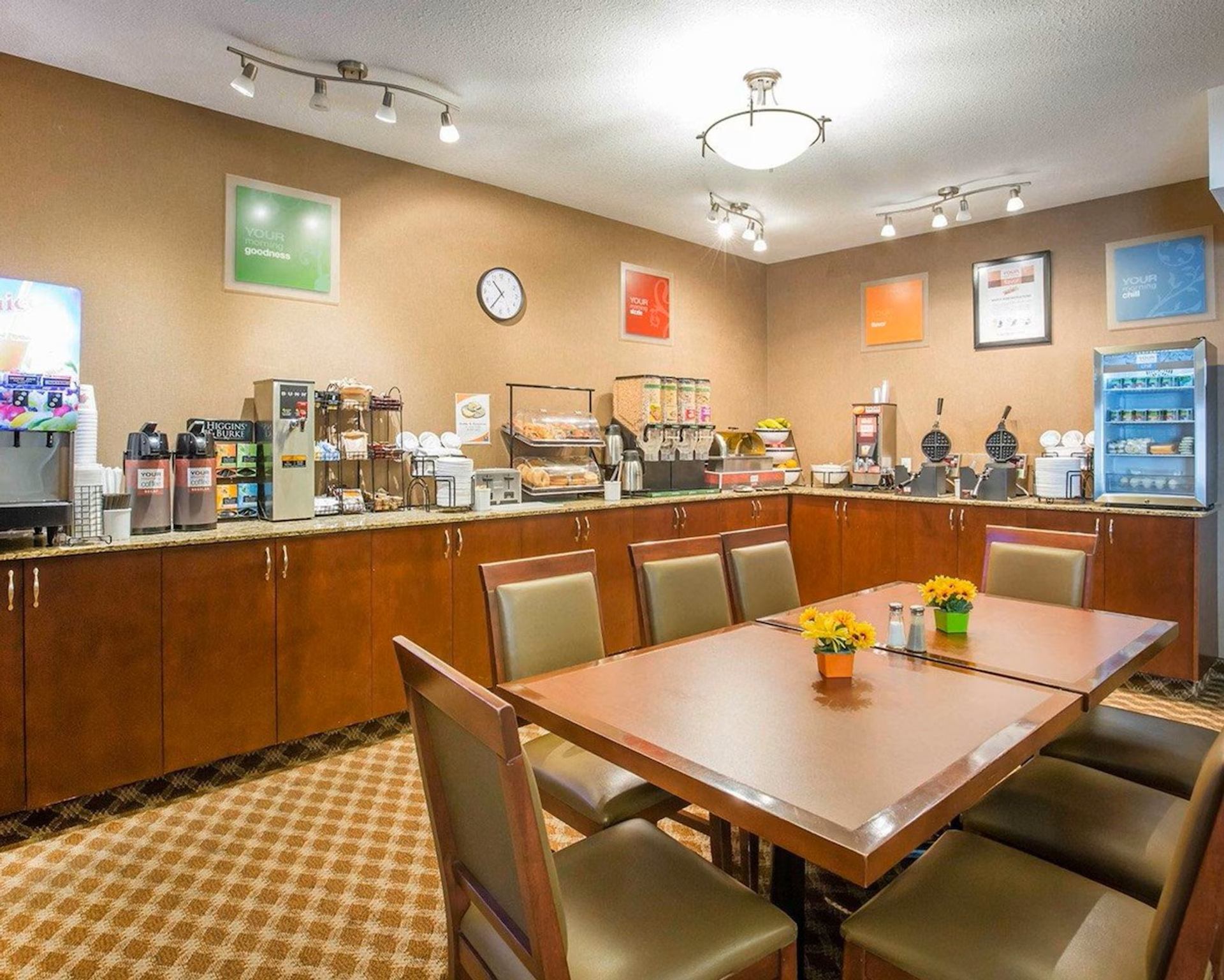 Breakfast seating area at Comfort Inn & Suites with tables, chairs, and a stocked buffet counter.
