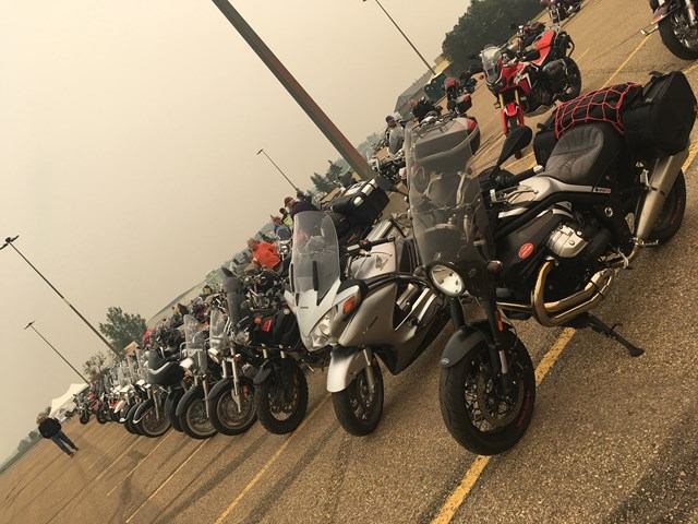 Motorcycle lineup parked on a road, with riders seated and bikes facing camera.