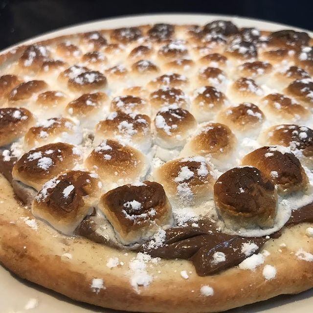 Dessert pizza topped with toasted marshmallows and powdered sugar.