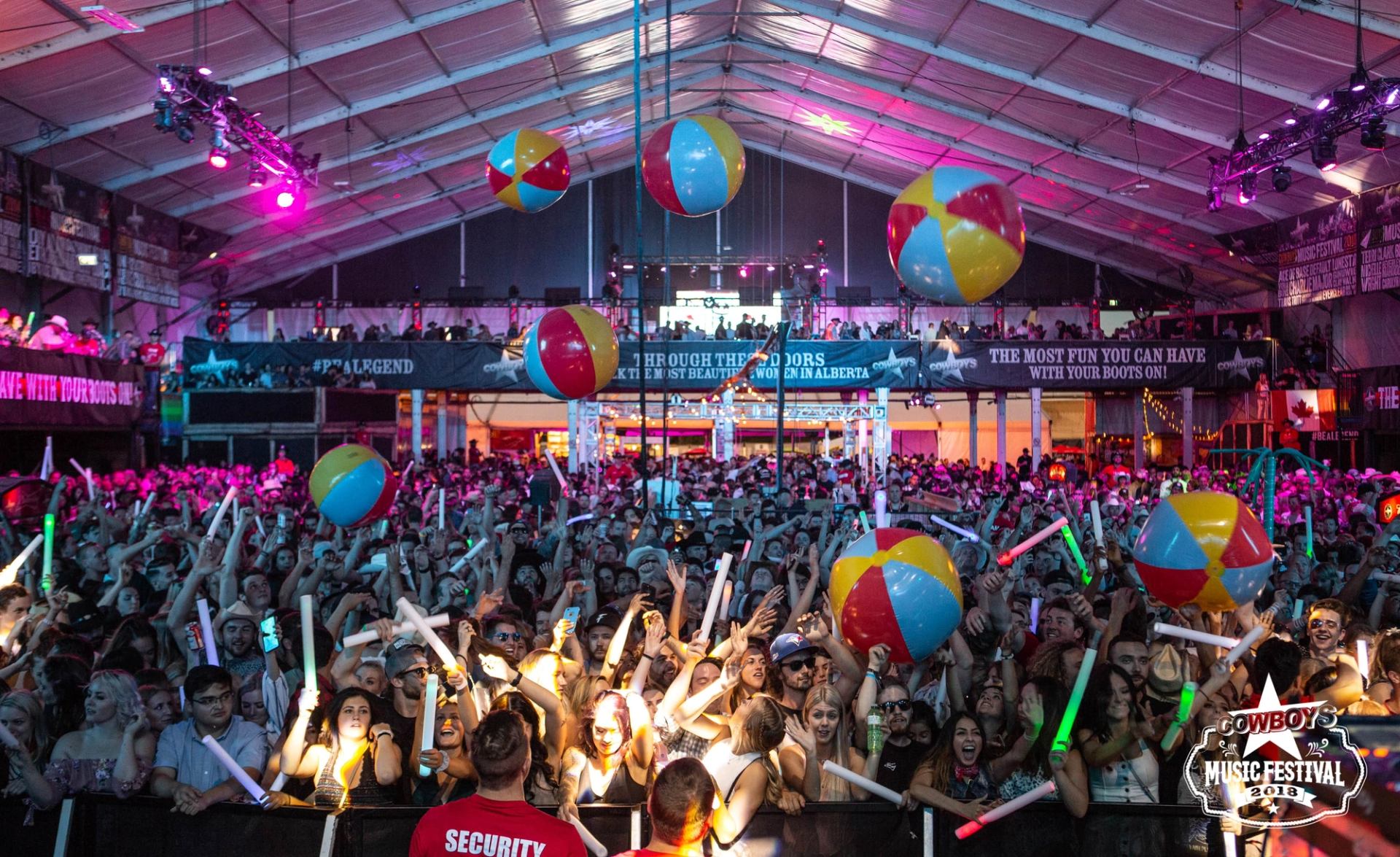 Several large beach balls bounce above a crowd in the Cowboys Music Festival tent.
