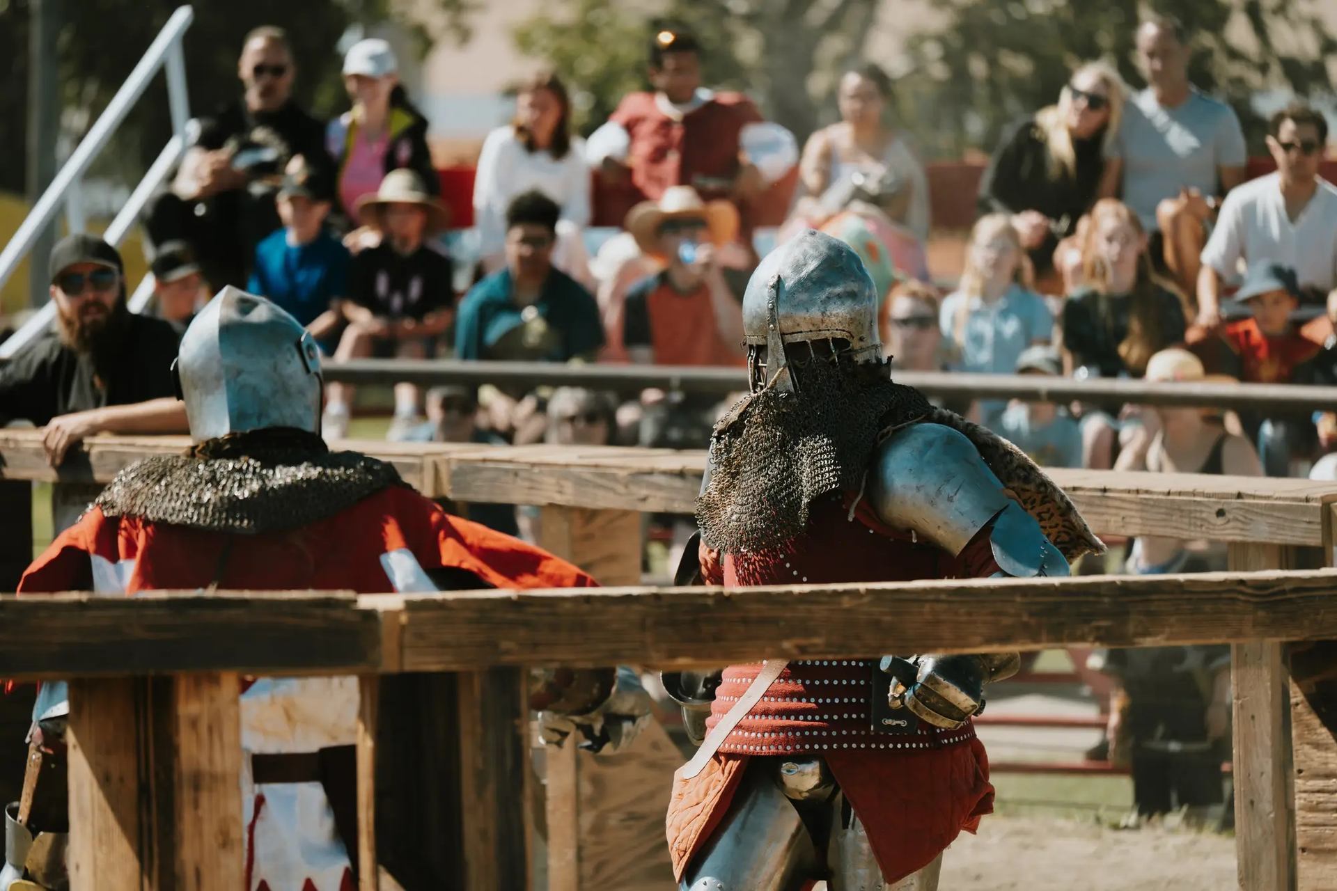 Armored fighters duel in arena at Vegreville Medieval Faire with crowd watching.