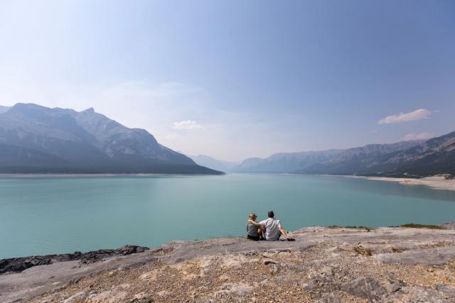 A couple look at into Abraham Lake.