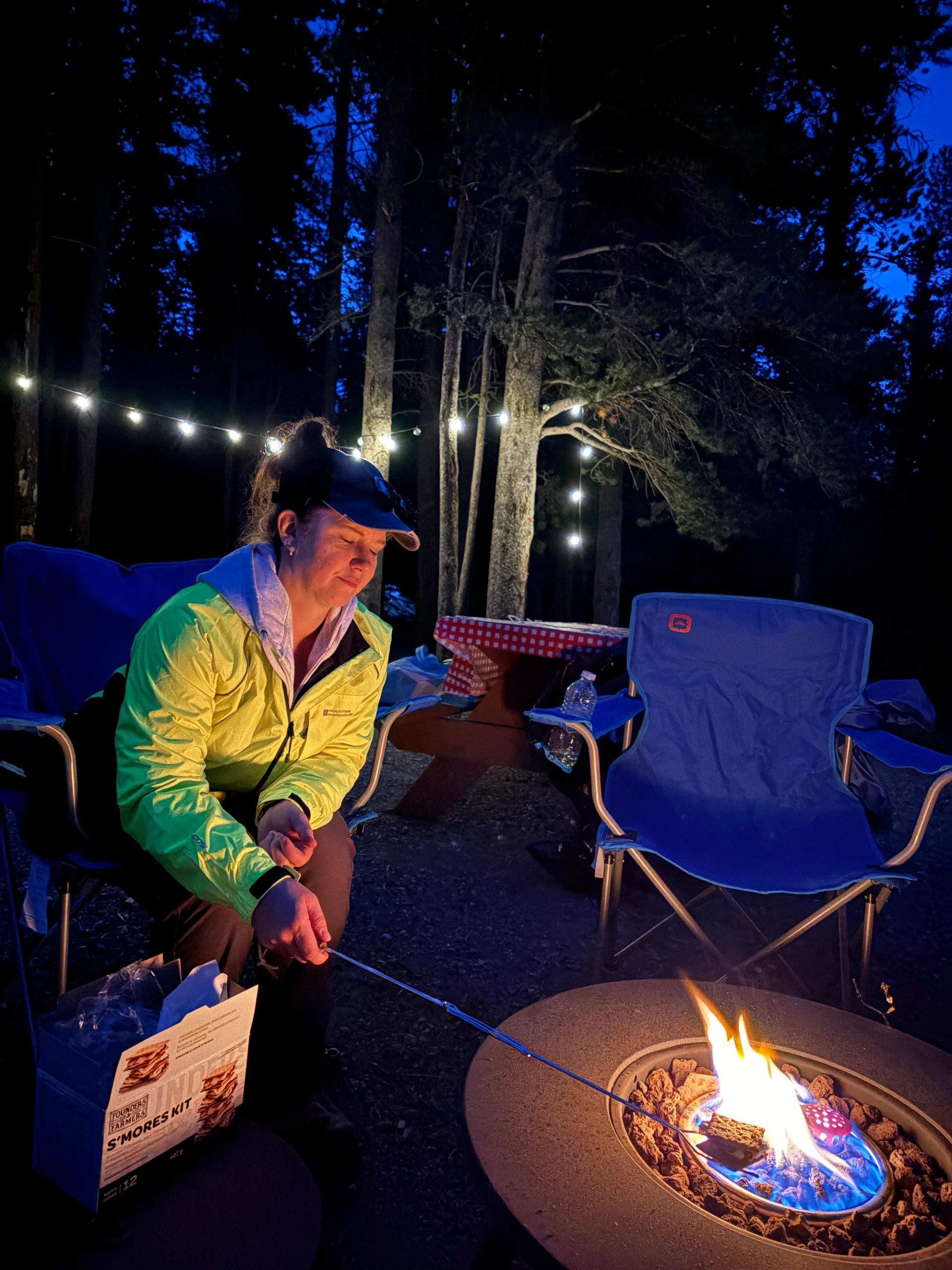 A person roasting marshmellows on an open fire while overnight camping.