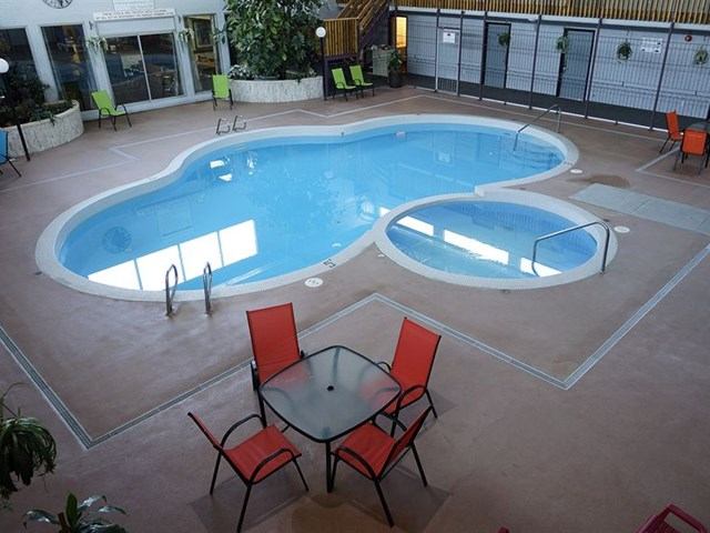 Indoor pool area with lounge chairs, tables, and natural light at Imperial Inn.