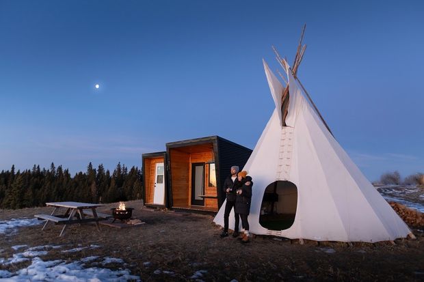 A couple out front of the cabins and tipi at Running Reins Ranch nearing sunset