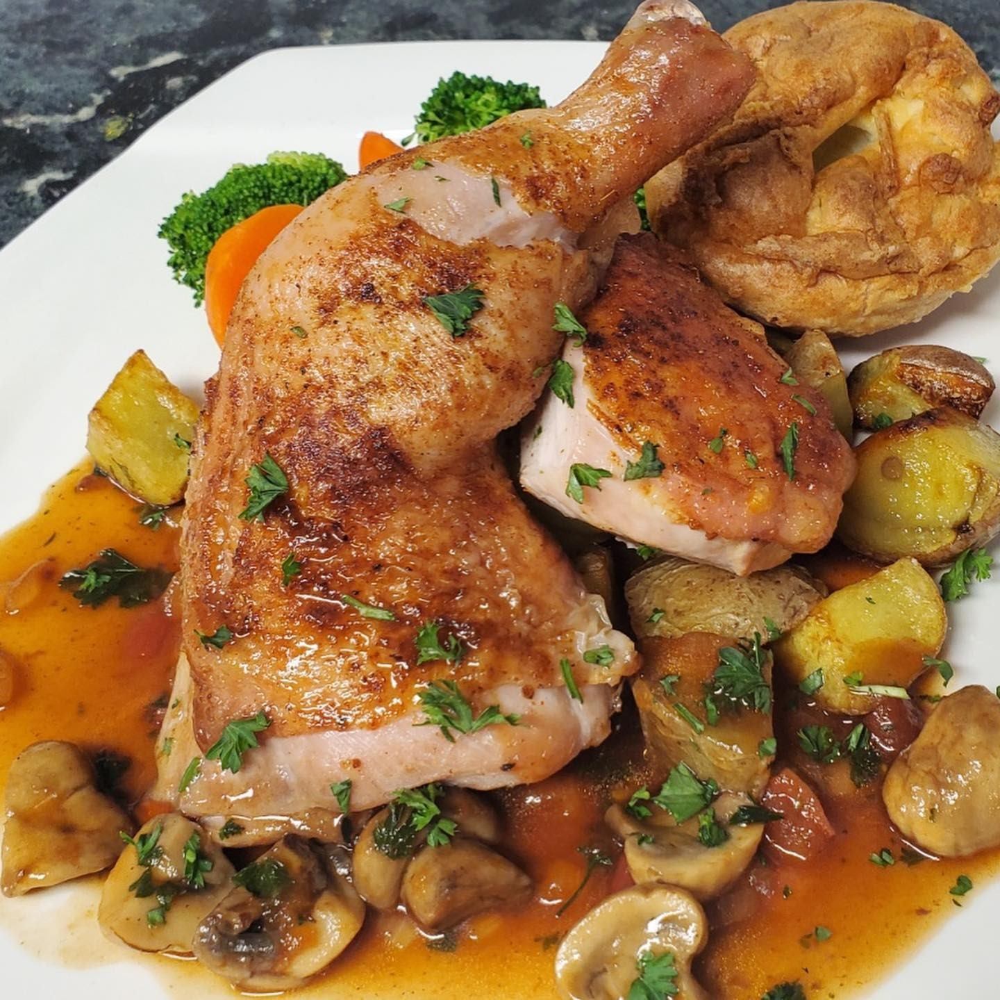 Roasted chicken with mushrooms, potatoes, Yorkshire pudding, and veggies in brown sauce.