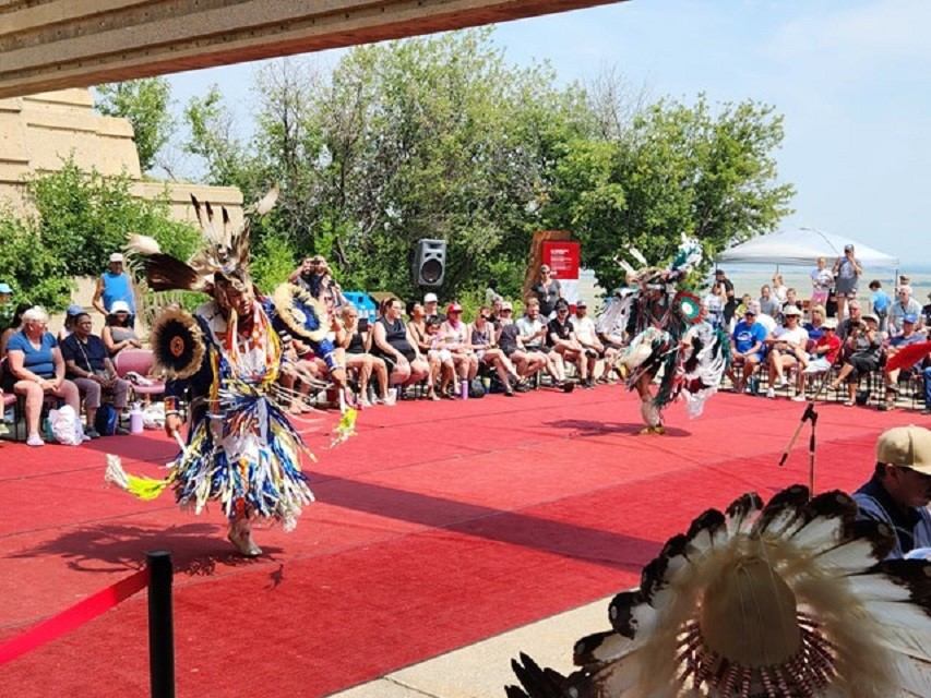 Two dancers in traditional attire performing on red carpet.