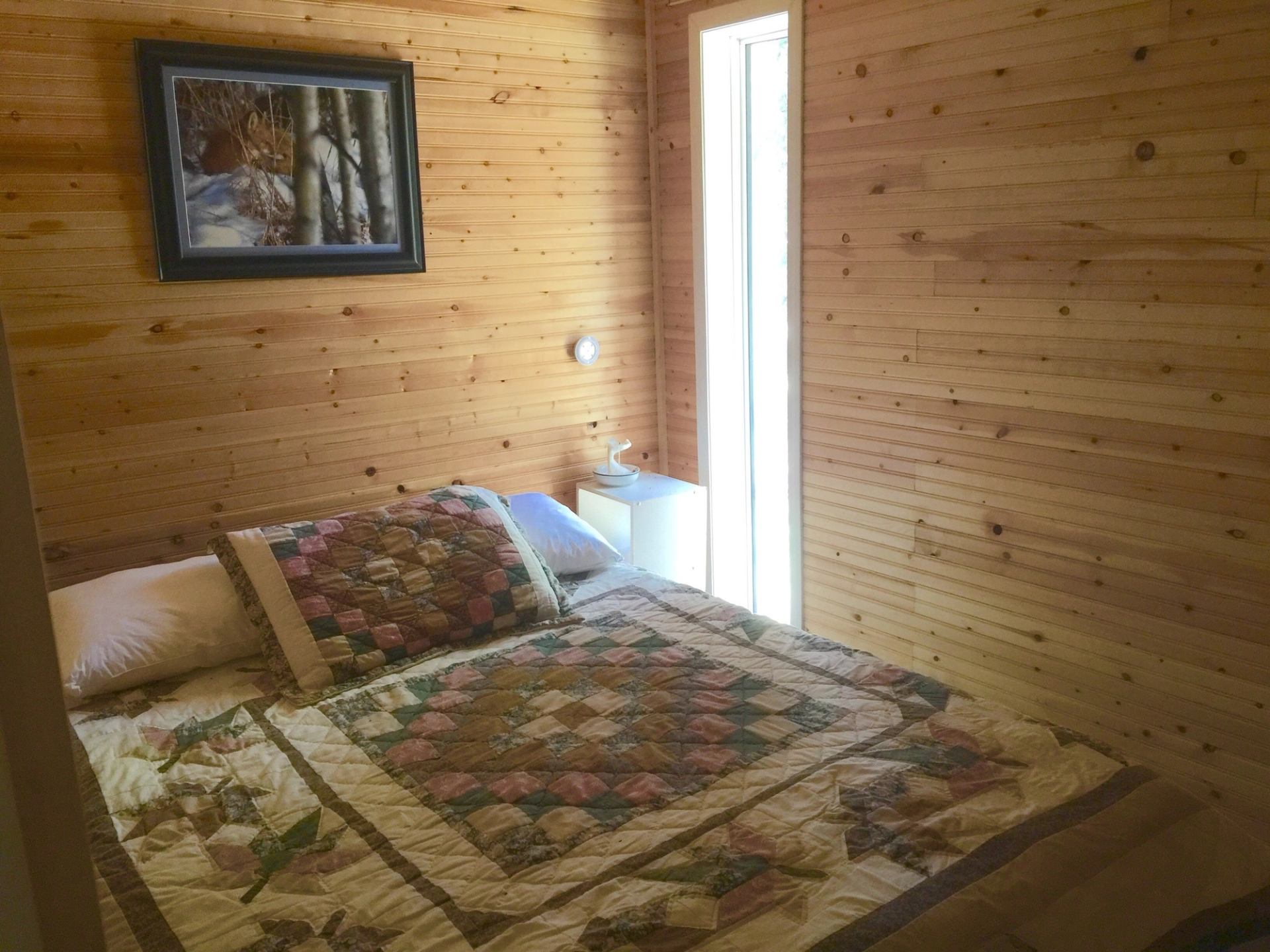 A bedroom at with homemade quilt and wooden walls.