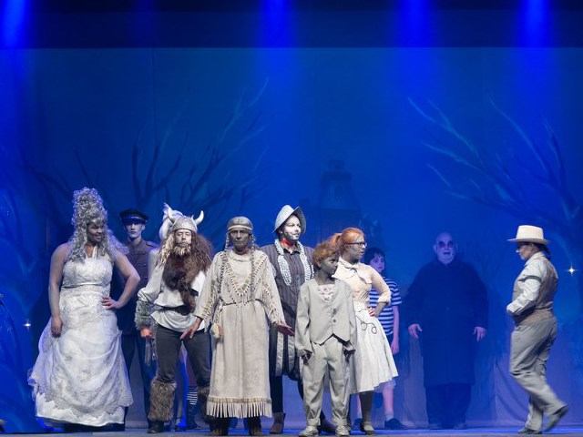 Stage cast in period costumes performing on blue theatre backdrop at Windmill Theatre Players.