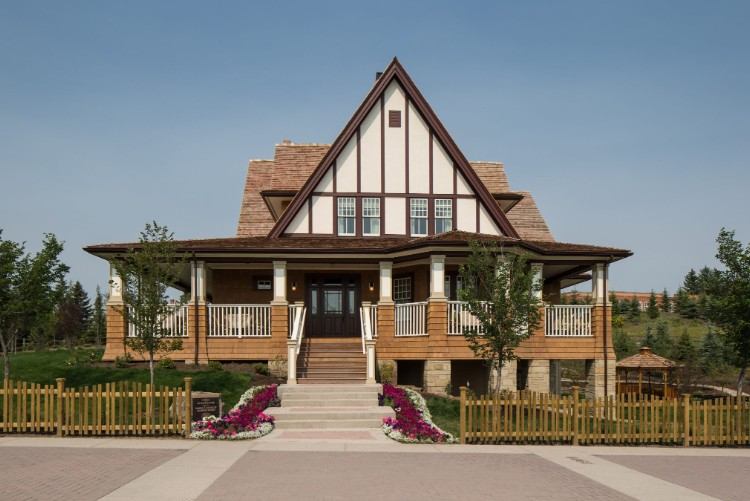 Two-storey Tudor-style house with large front porch, wooden fence and landscaped garden