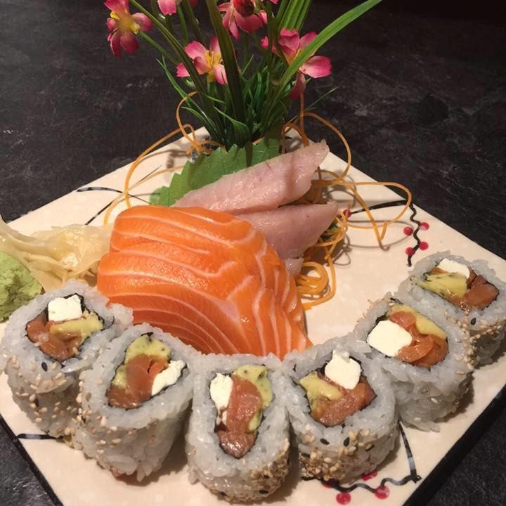 Plate with sushi rolls, salmon sashimi, and decorative garnish