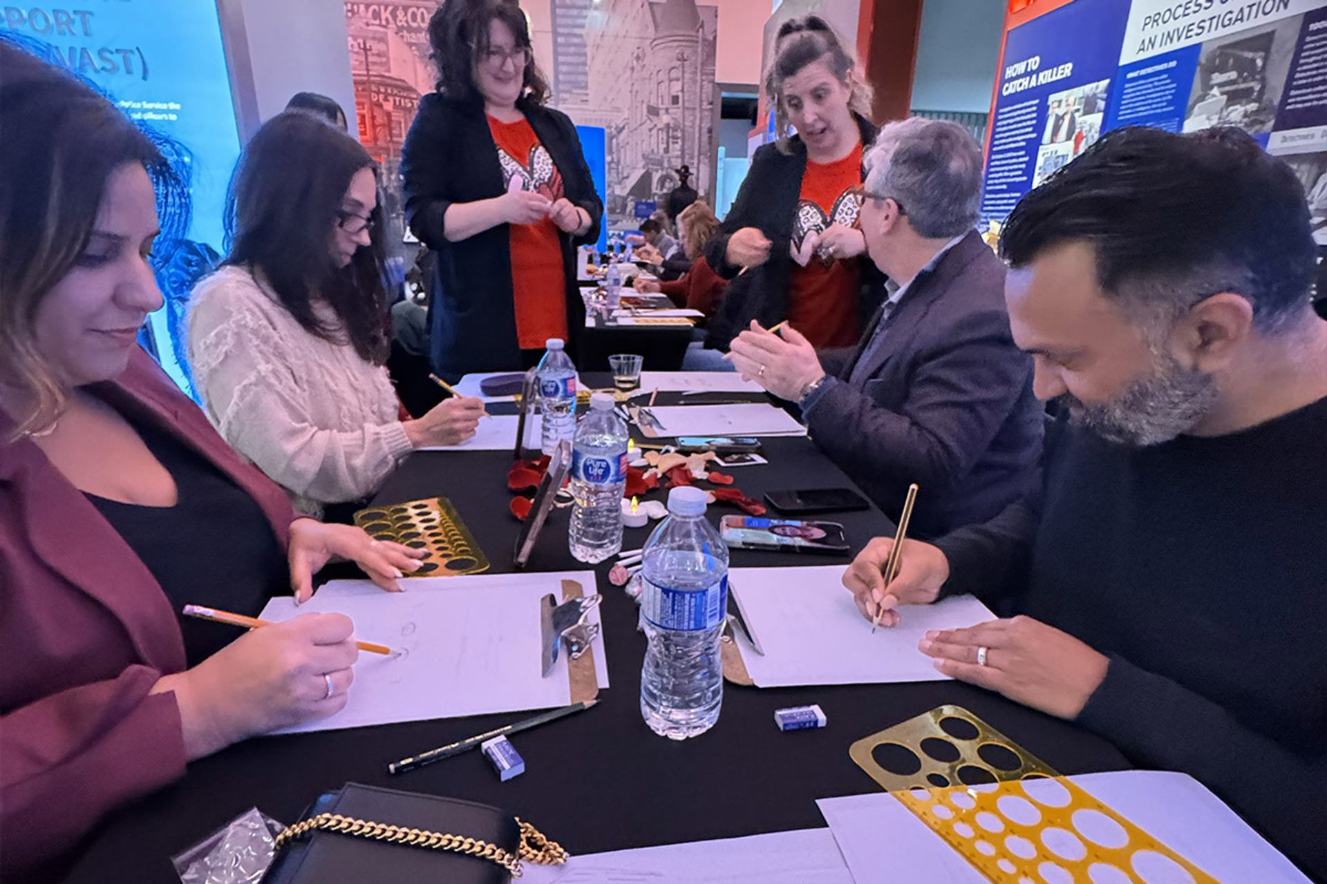 Group seated at a table sketching during a true crime-themed Sip & Sketch event.