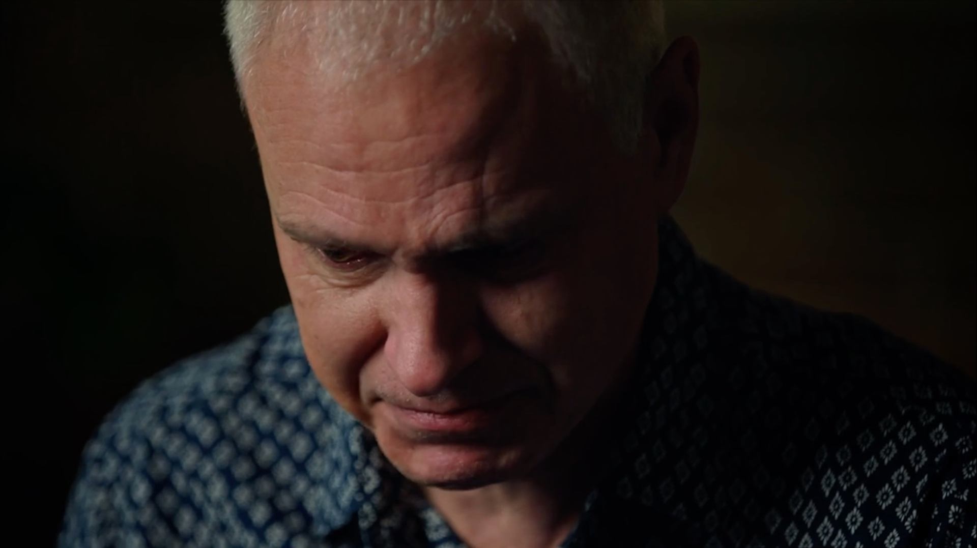 Close-up of Delwin Vriend looking downward in a patterned shirt.