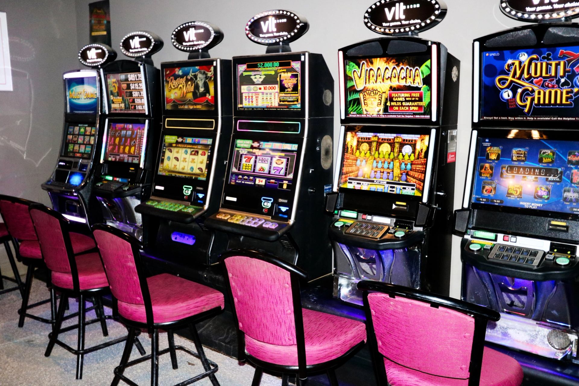 Row of VLT slot machines with pink chairs in front.