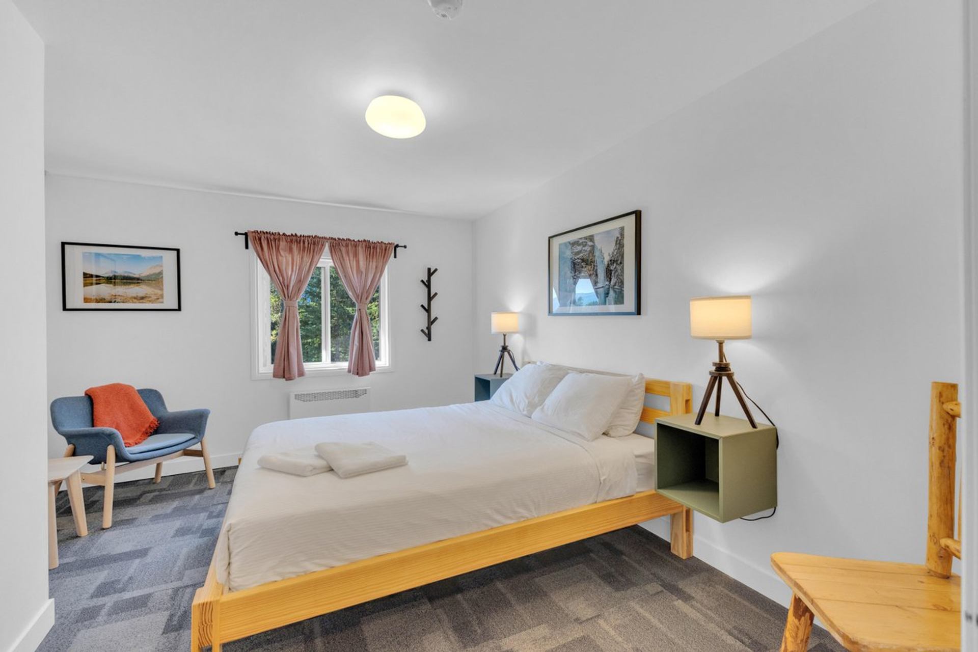 Bright guest room with a wooden bed, white bedding, and a seating area near a window.
