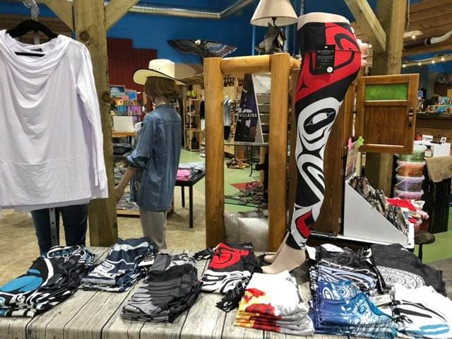 General store display with shirts, hats, and folded garments on a wooden table and rack.