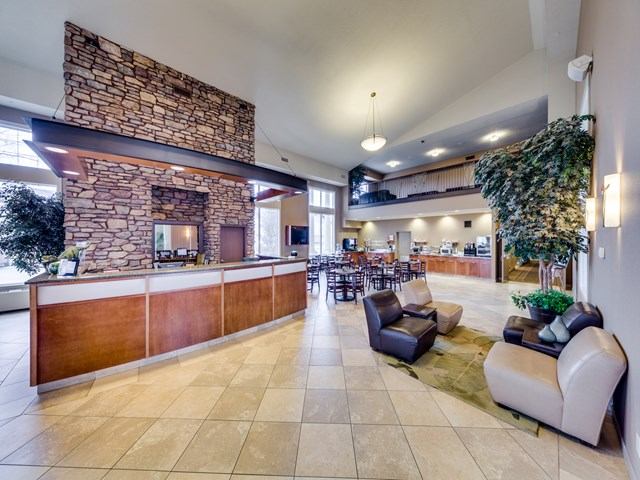 Spacious hotel lobby with stone fireplace, seating area, and dining tables.