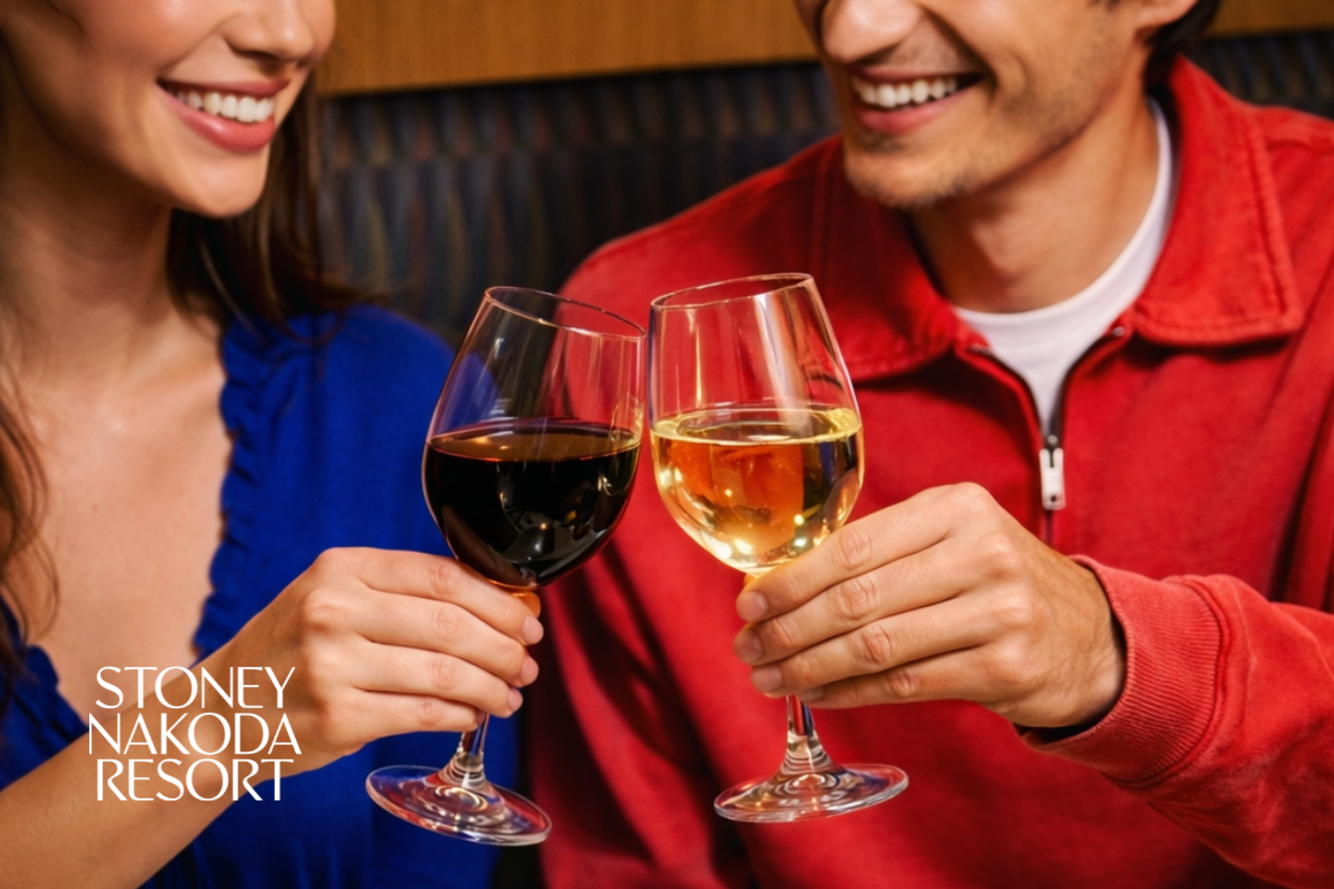 A smiling couple clinking glasses of red and white wine.