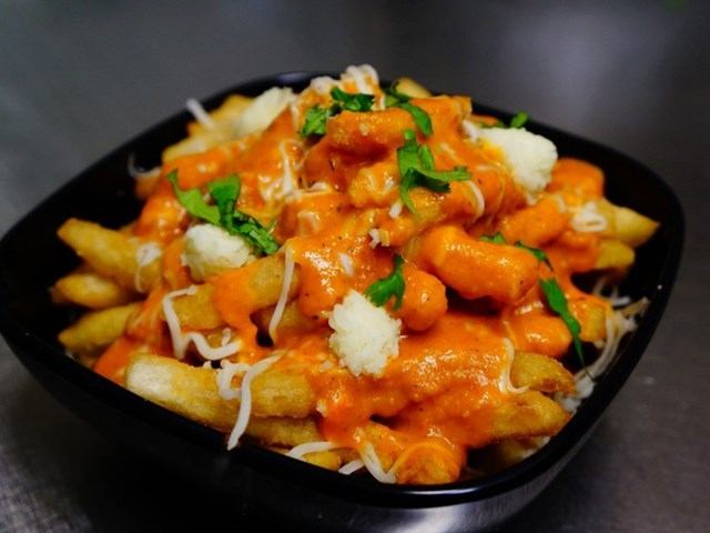 Fries topped with creamy orange sauce, cheese, and herbs at Tandoor n Flame.