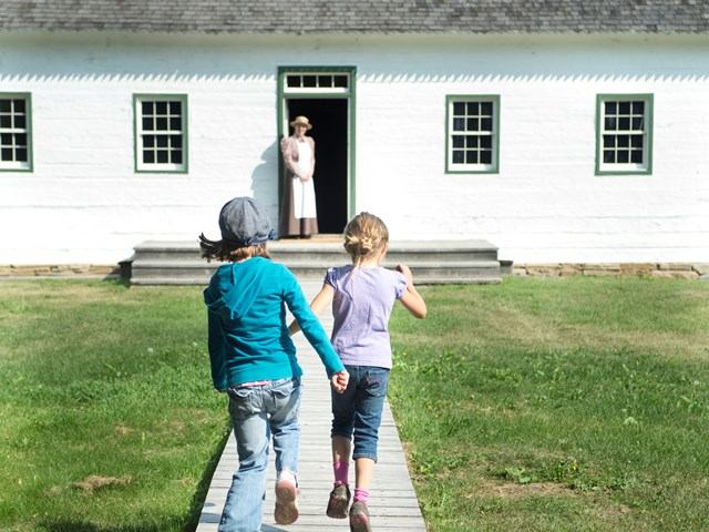 Children walking toward a historic building at Historic Dunvegan.