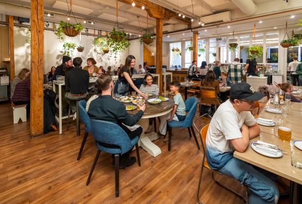 Server puts a drink down on the table for a family while dining in a busy Ten Foot Henry.