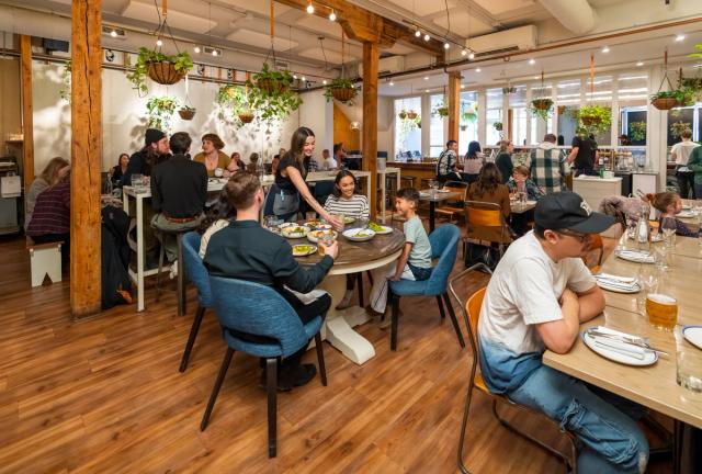 Server puts a drink down on the table for a family while dining in a busy Ten Foot Henry.