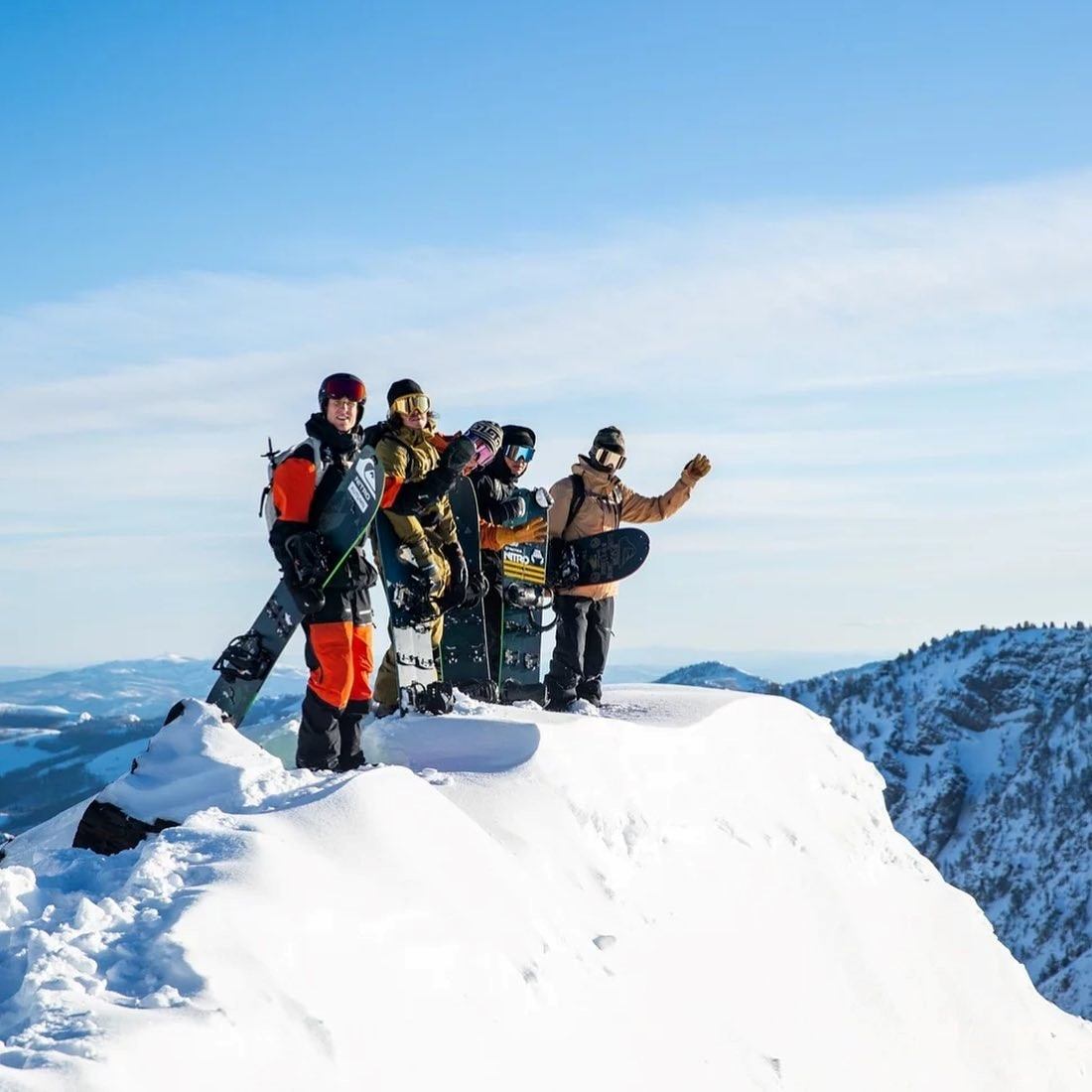 Group of snowshoers posing on a snowy mountain ridge with skis and poles.