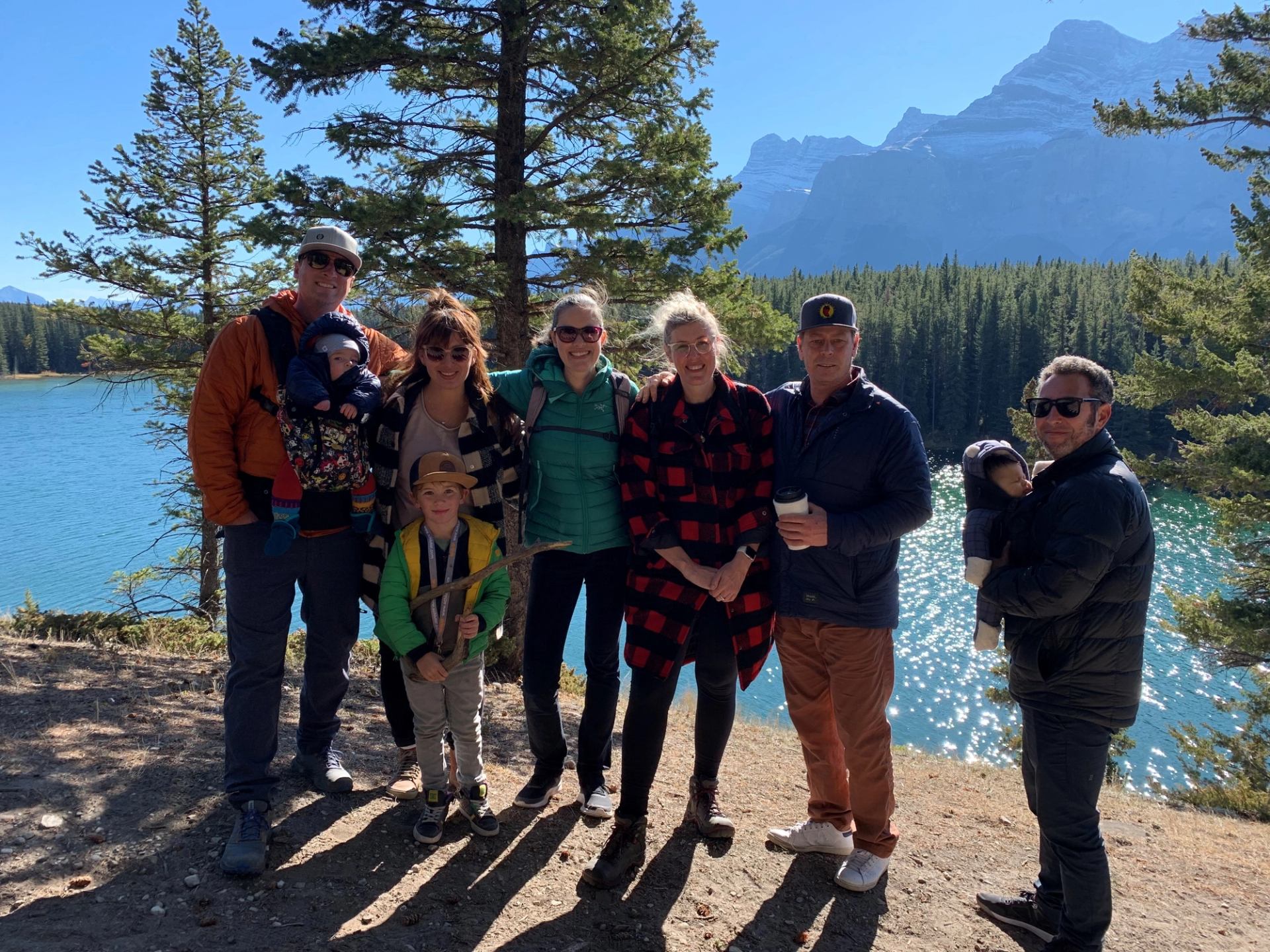 group of people standing in front of a mountain lake